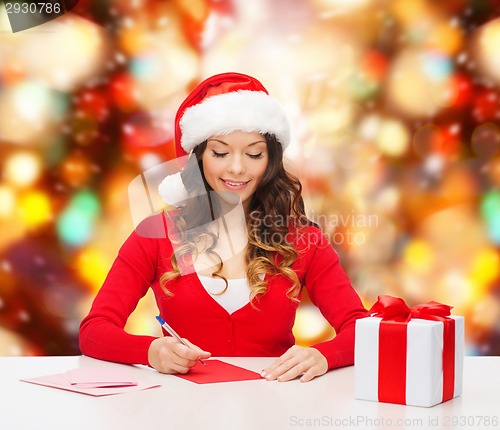 Image of smiling woman with gift box writing letter