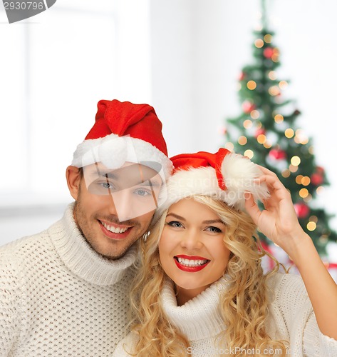 Image of smiling couple in sweaters and santa helper hats