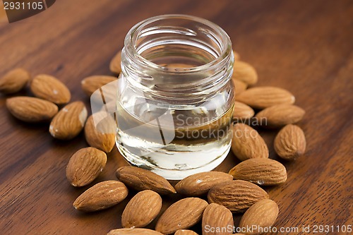 Image of Almond oil with nuts on wooden background