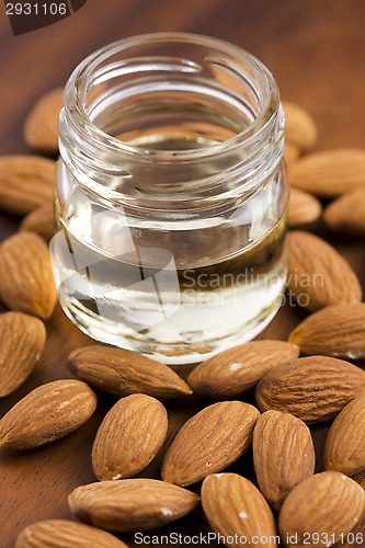 Image of Almond oil with nuts on wooden background