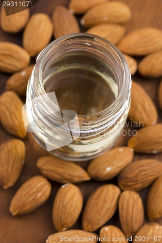 Image of Almond oil with nuts on wooden background