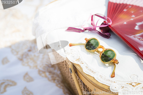 Image of Sunglasses, Chinese Fan and Picnic Basket on Blanket