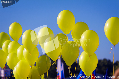 Image of The yellow rubber balloons filled with gas against the blue sky.