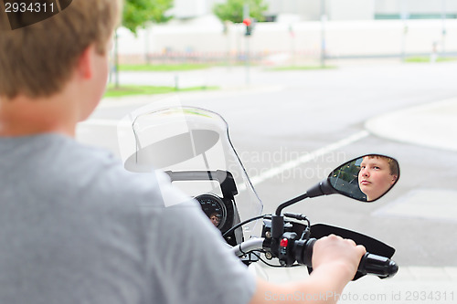 Image of Teenager riding a motorcycle at street junction