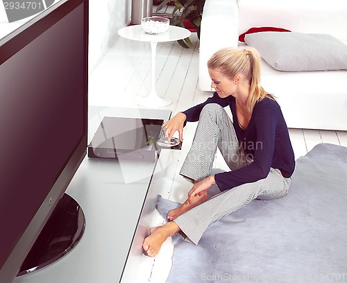 Image of woman using dvd player in flat