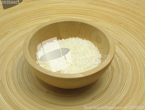 Image of Wooden bowl with coconut flakes on bamboo plate