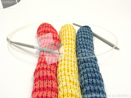 Image of Three striped  knitting scarfs with needle on white