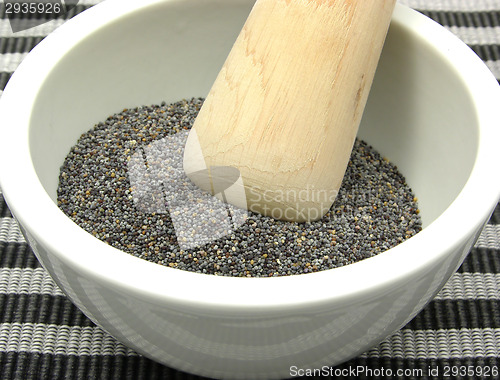 Image of Pestling poppy seeds  in a bowl of chinaware