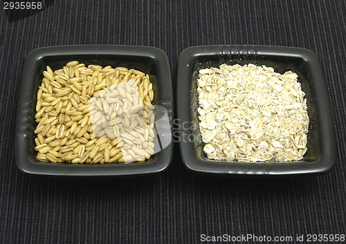 Image of Oat and flakes in bowls of chinaware on black mat