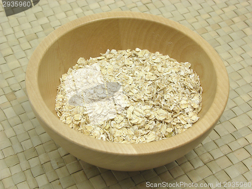 Image of Wooden bowl with oat flakes on rattan underlay