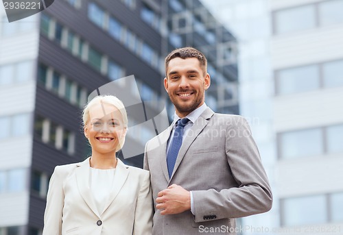 Image of smiling businessmen standing over office building