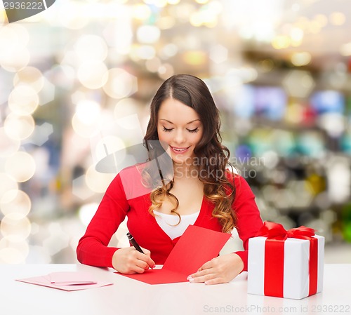 Image of smiling woman with gift box writing letter