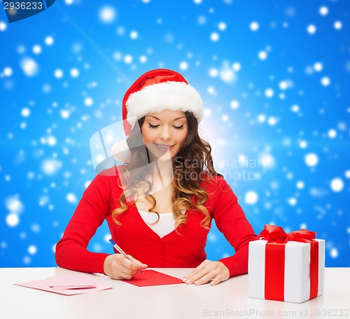 Image of smiling woman with gift box writing letter