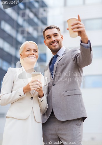 Image of smiling businessmen with paper cups outdoors