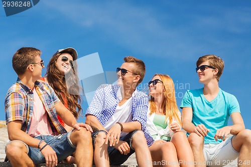 Image of group of smiling friends sitting on city street