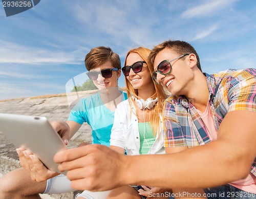Image of group of smiling friends with tablet pc outdoors