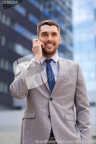 Image of smiling businessman with smartphone outdoors