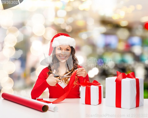 Image of smiling woman in santa helper hat packing gift box