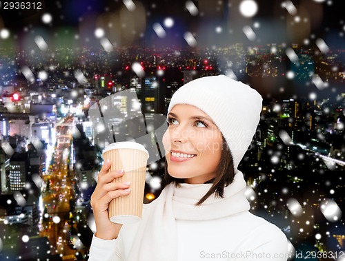Image of smiling young woman in winter clothes with cup