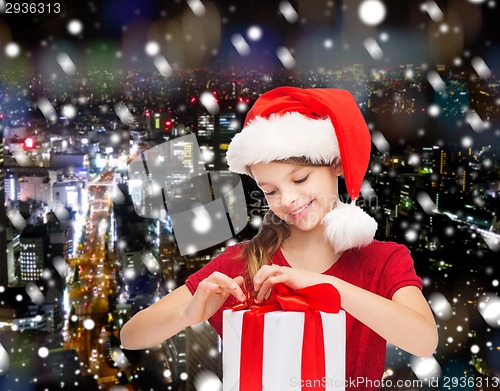 Image of smiling girl in santa helper hat with gift box