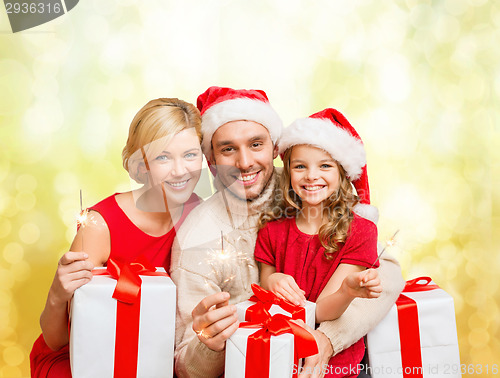 Image of smiling family holding gift boxes and sparkles