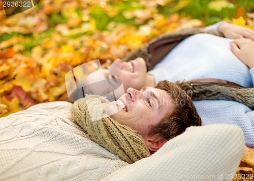 Image of close up of smiling couple lying in autumn park