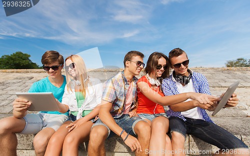 Image of group of smiling friends with tablet pc outdoors