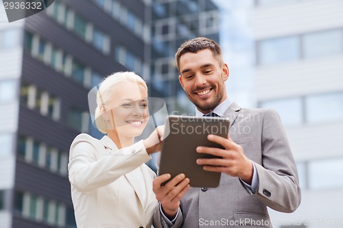 Image of smiling businessmen with tablet pc outdoors