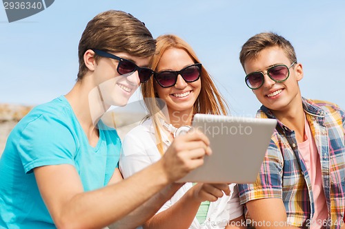 Image of group of smiling friends with tablet pc outdoors