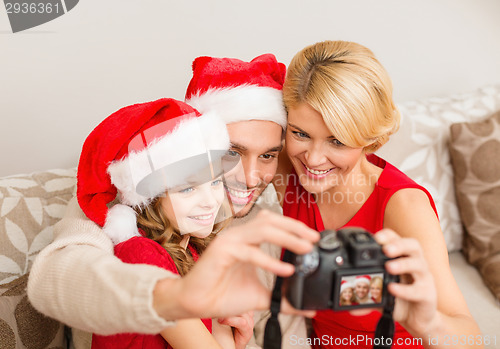 Image of smiling family in santa helper hats taking picture