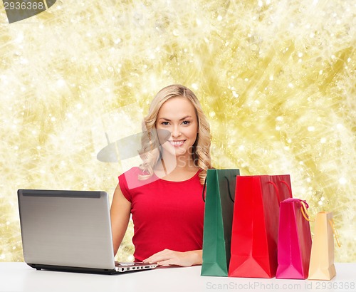 Image of smiling woman in red shirt with gifts and laptop