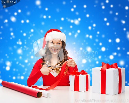 Image of smiling woman in santa helper hat packing gift box