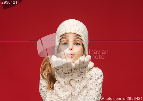 Image of happy girl in winter clothes blowing on palms