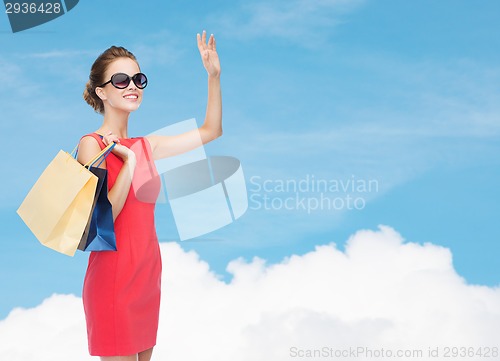 Image of smiling elegant woman in dress with shopping bags