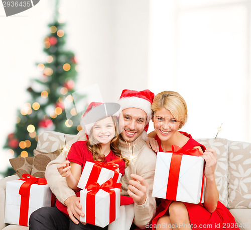 Image of smiling family holding gift boxes and sparkles