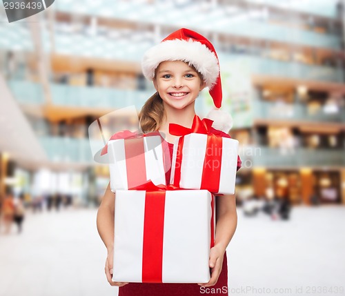 Image of smiling little girl in santa helper hat with gifts