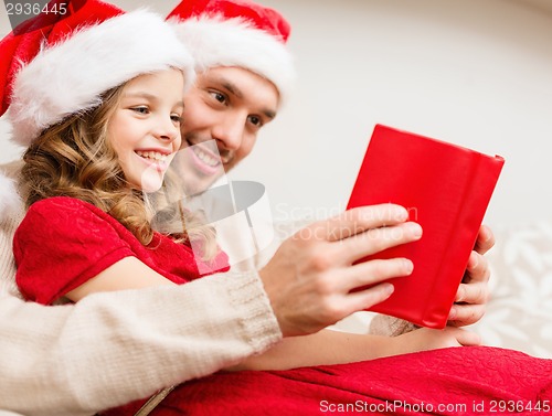 Image of smiling father and daughter reading book