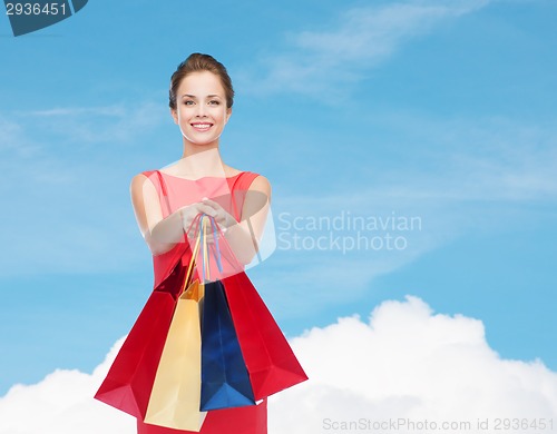 Image of smiling elegant woman in dress with shopping bags