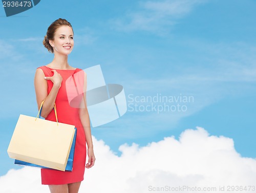 Image of smiling elegant woman in dress with shopping bags