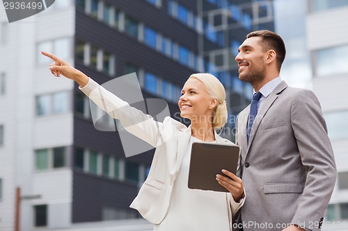 Image of smiling businessmen with tablet pc outdoors