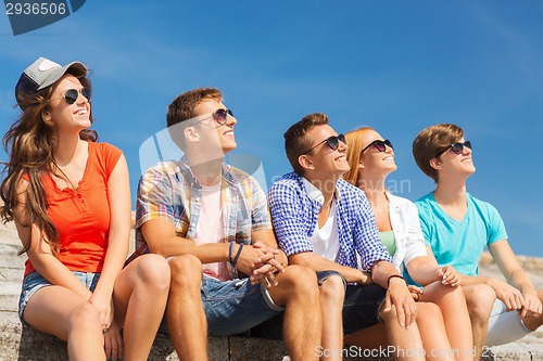 Image of group of smiling friends sitting on city street