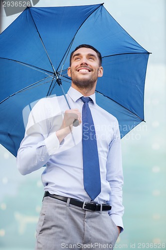 Image of young smiling businessman with umbrella outdoors