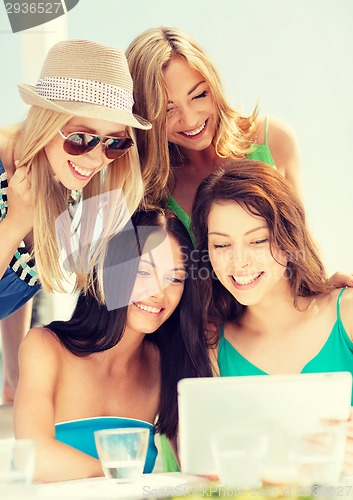 Image of smiling girls looking at tablet pc in cafe