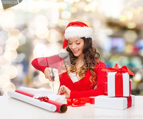 Image of smiling woman in santa helper hat packing gift box
