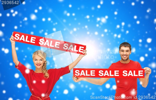 Image of smiling man and woman with red sale signs