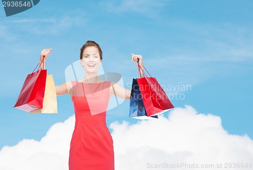Image of laughing elegant woman in dress with shopping bags