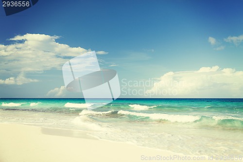 Image of blue sea or ocean, white sand and sky with clouds