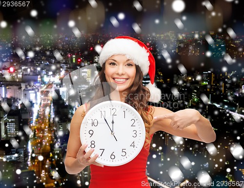 Image of smiling woman in santa helper hat with clock