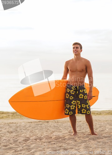 Image of smiling young man with surfboard on beach