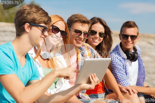 Image of group of smiling friends with tablet pc outdoors